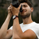 Professional photographer taking picture. young man with a camera. a man takes a photo with a professional camera in nature.